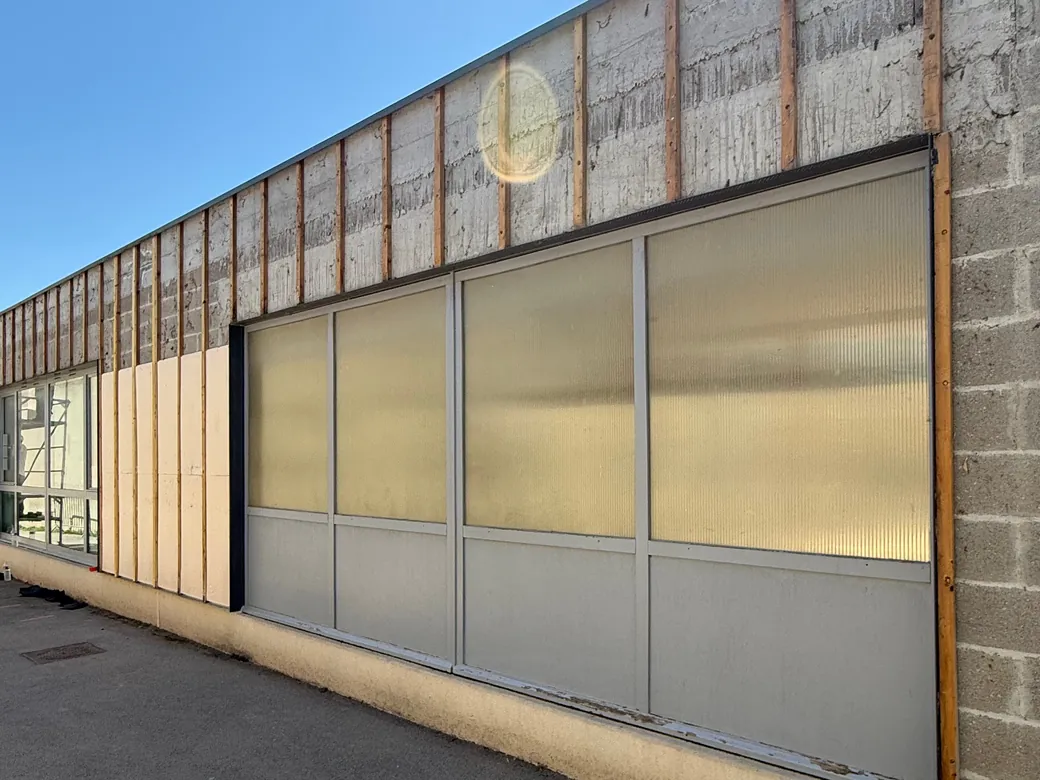 Détail : ossature bois verticale et lame d'air ventilée sur le mur support, avant la pose des nouveaux panneaux