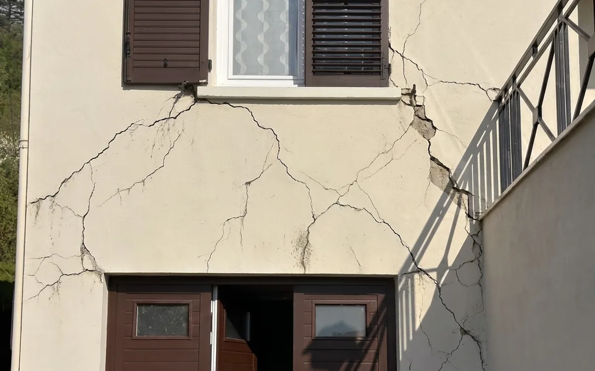 Illustration : fissures et lézardes sur un enduit de façade, réseau de fissures autour d'une fenêtre