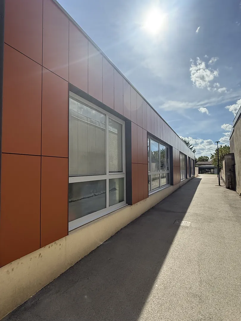 Nouveau bardage ventilé posé par NFR sur l'école de Viriat, panneaux orange terre cuite de la même teinte que l'ancien, le long de l'allée
