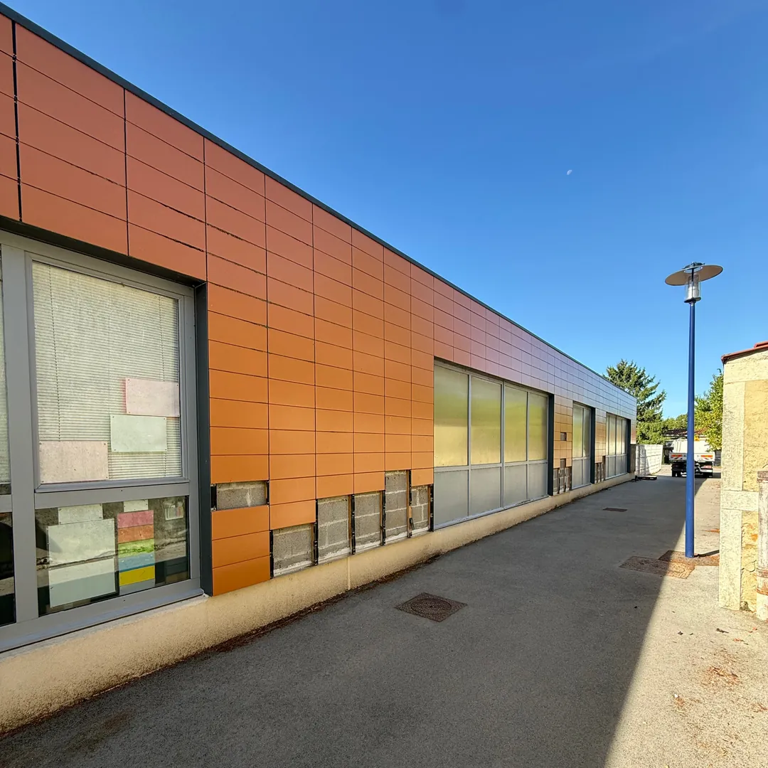École de Viriat avant travaux : ancien bardage orange terre cuite abîmé, panneaux du bas manquants et parpaings à nu