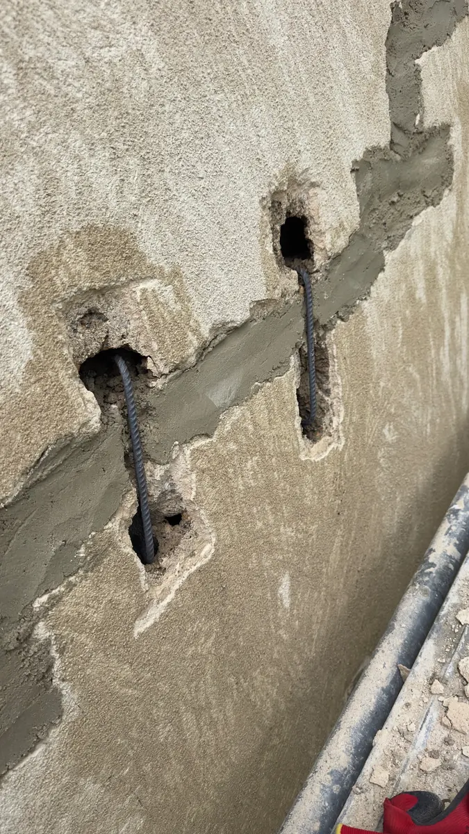 Fissure ouverte sur un pignon à Beaupont, deux agrafes en acier scellées en travers avant rebouchage, chantier NFR