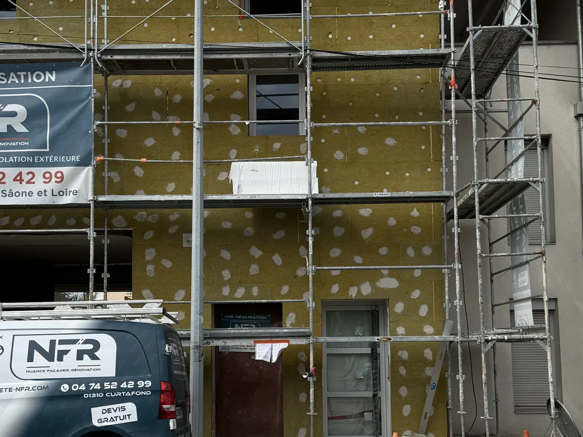 Façade couverte de panneaux isolants sous échafaudage, panneau NFR au centre