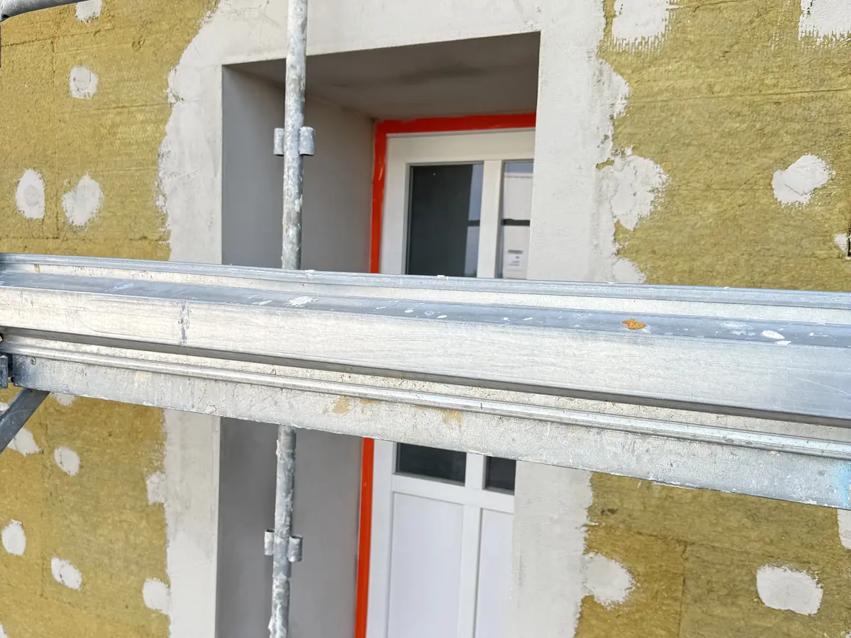 Détail d'une baie à Bourg-en-Bresse : laine de roche ajustée autour de la fenêtre, retours d'isolant en tableau