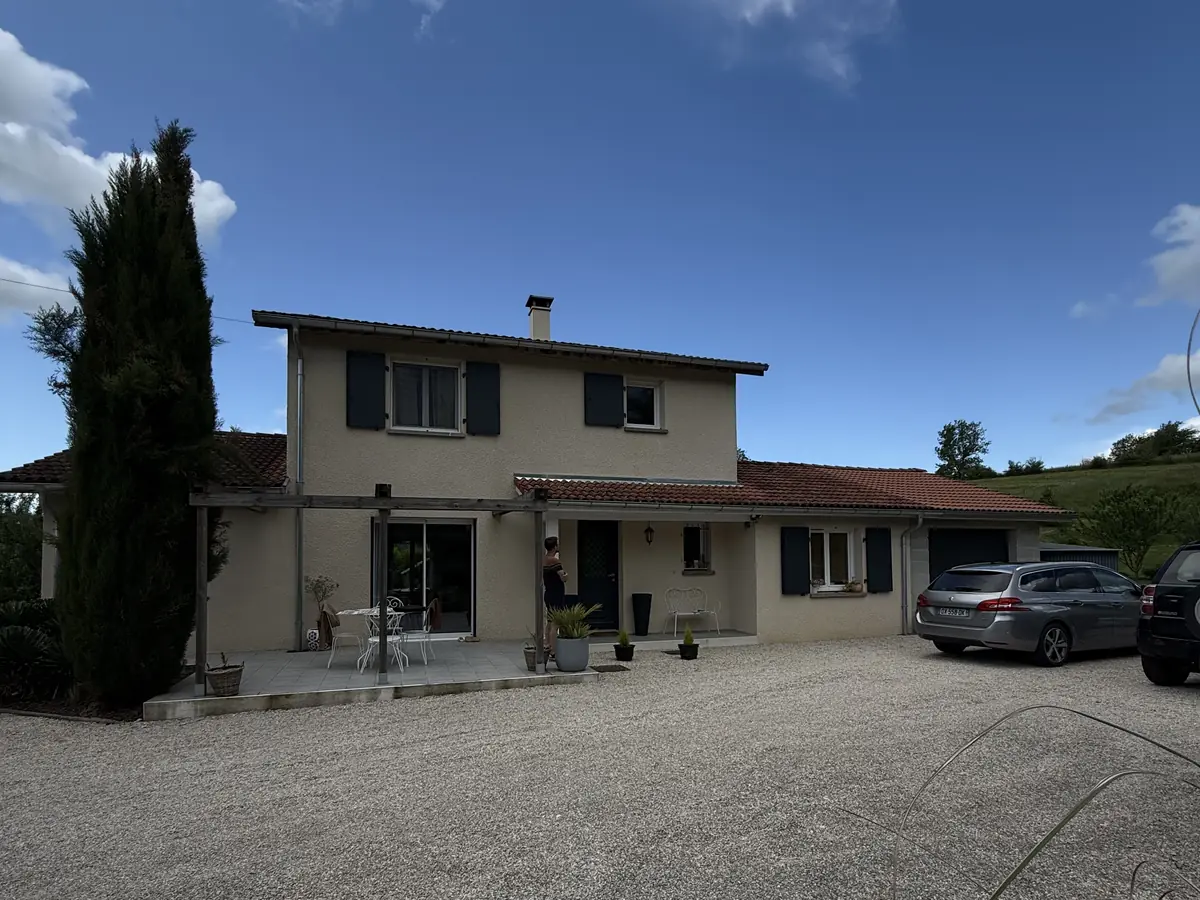 Maison à étage isolée par l'extérieur et enduite en beige clair, cyprès et allée gravillonnée