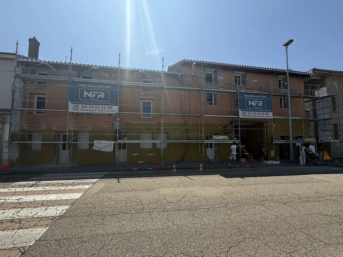 Façade de Bourg-en-Bresse sous échafaudage pendant la pose des panneaux isolants, deux banderoles NFR