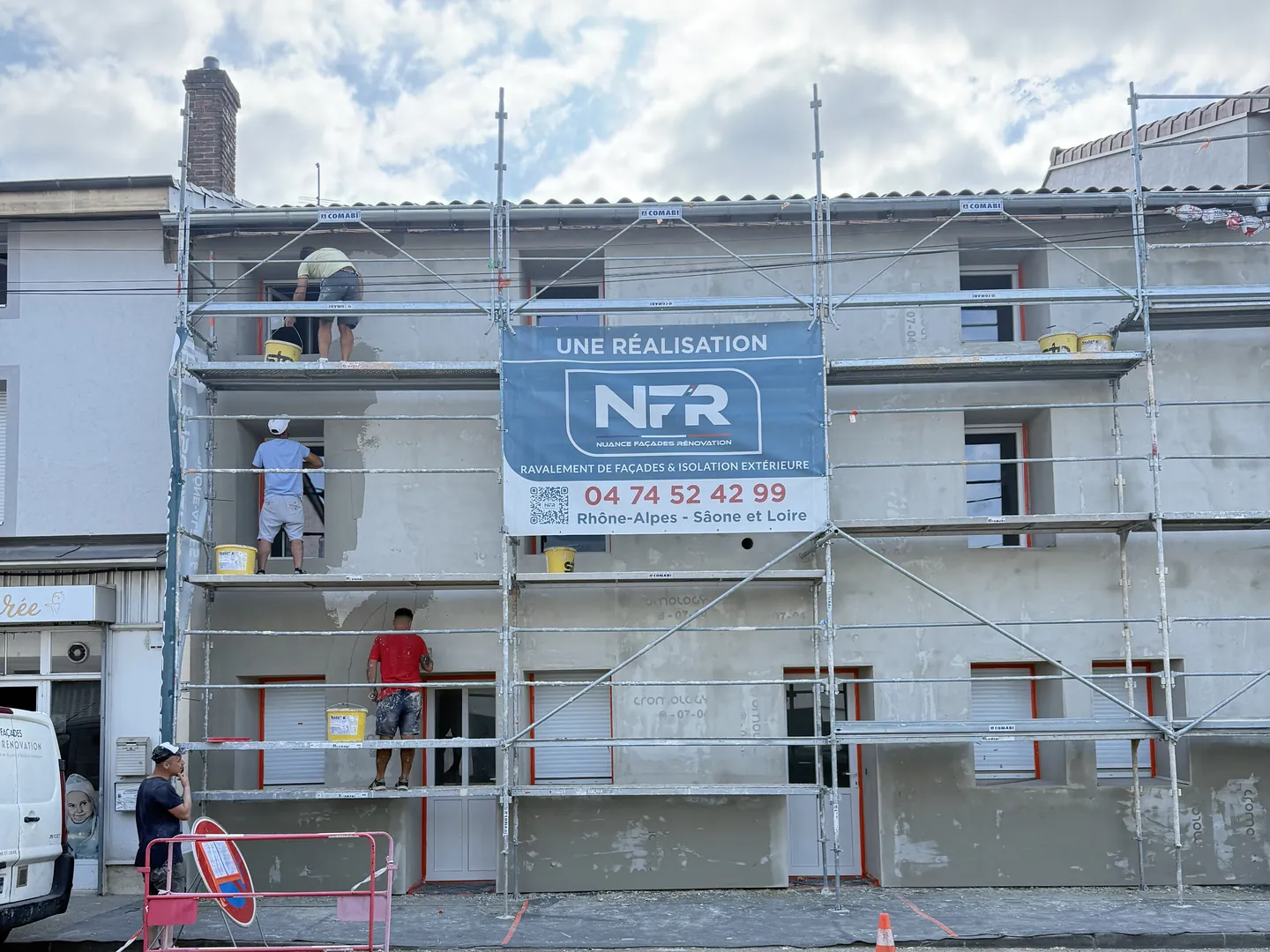 Artisans NFR sur l'échafaudage appliquant le sous-enduit sur l'isolant, banderole NFR