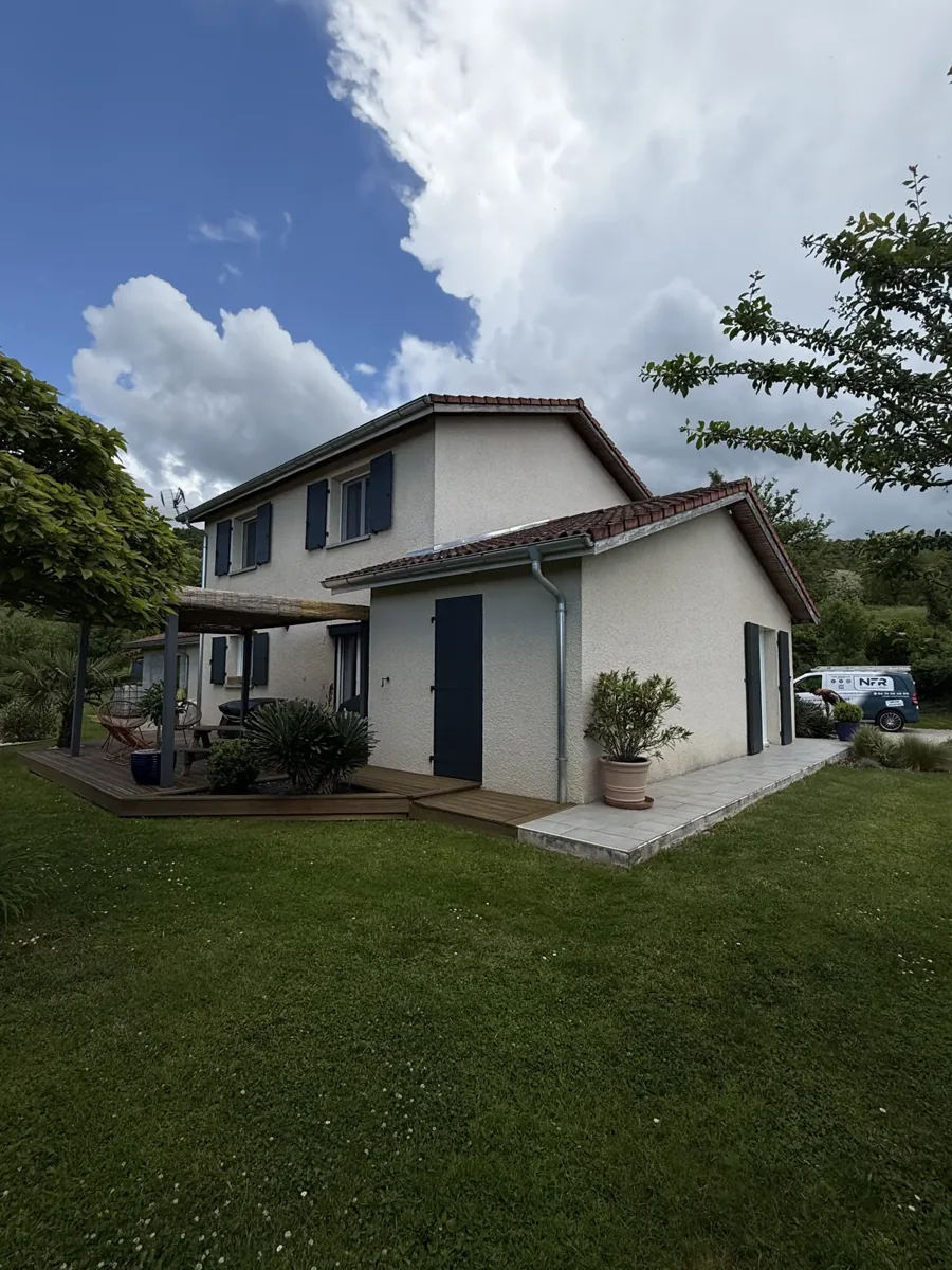 Maison rénovée à l'enduit clair et volets bleus, terrasse bois et jardin
