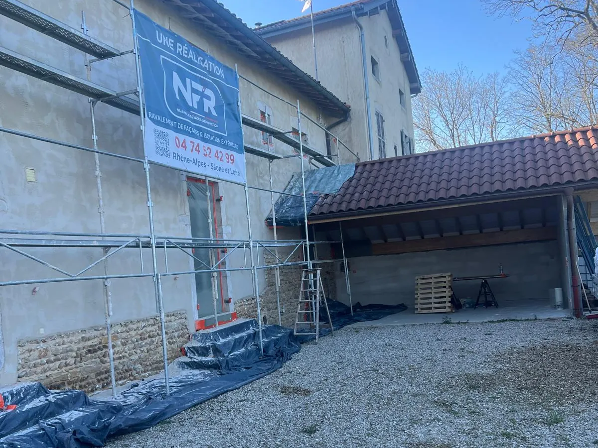Chantier NFR à L'Abergement sous échafaudage, banderole NFR : soubassement en pierre jointoyé, enduit à la chaux au-dessus