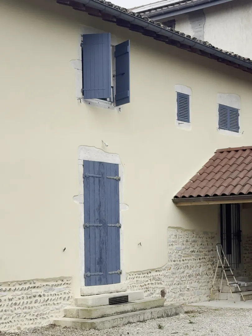 Mur enduit à Buellas, grand volet bleu et soubassement en pierre