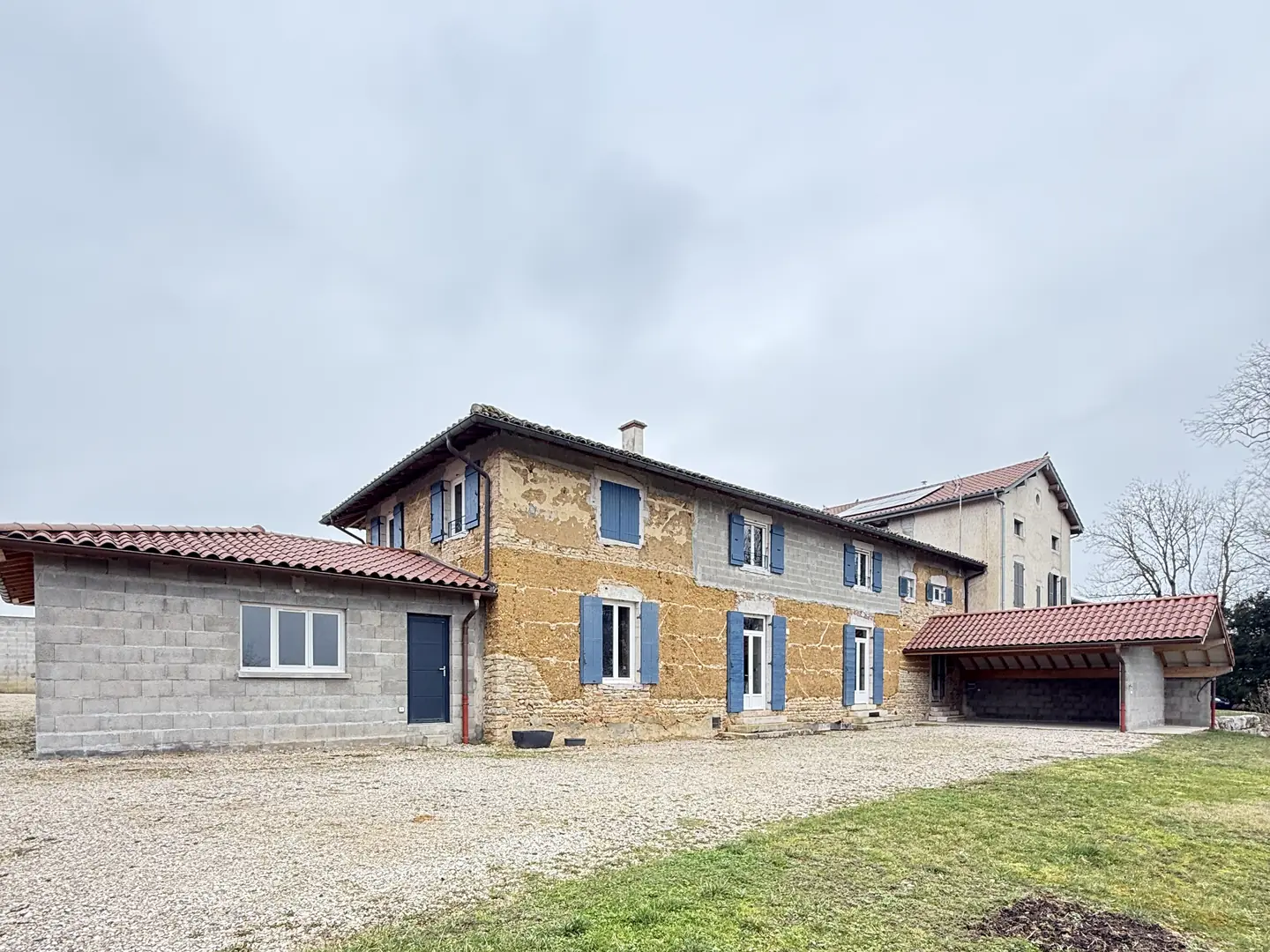 Maison en pisé à Buellas avant travaux, murs de terre et de pierre à nu, volets bleus