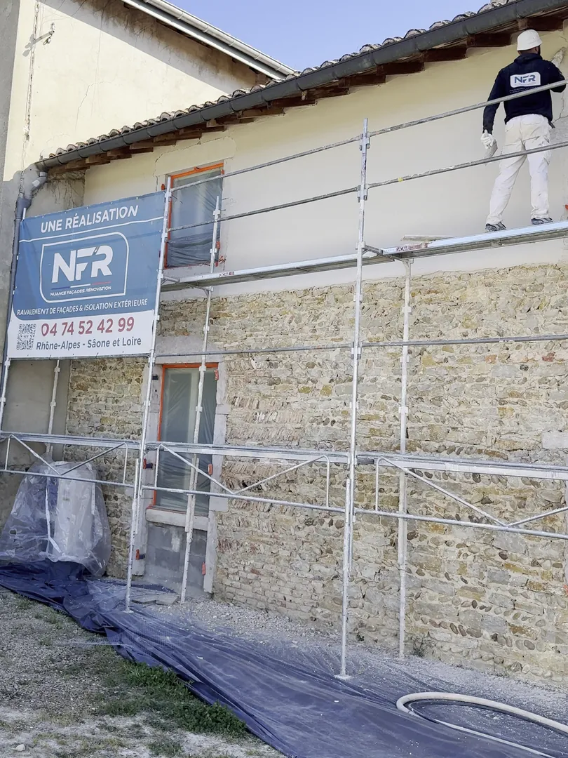 Artisan NFR sur l'échafaudage d'un mur en pierre et pisé, banderole NFR Une réalisation