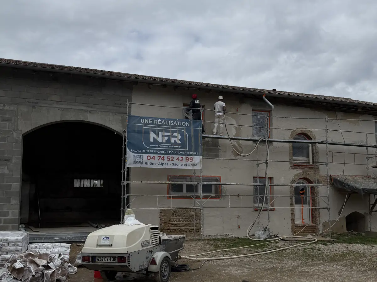 Ferme en pisé sous échafaudage avec banderole NFR, chantier en cours