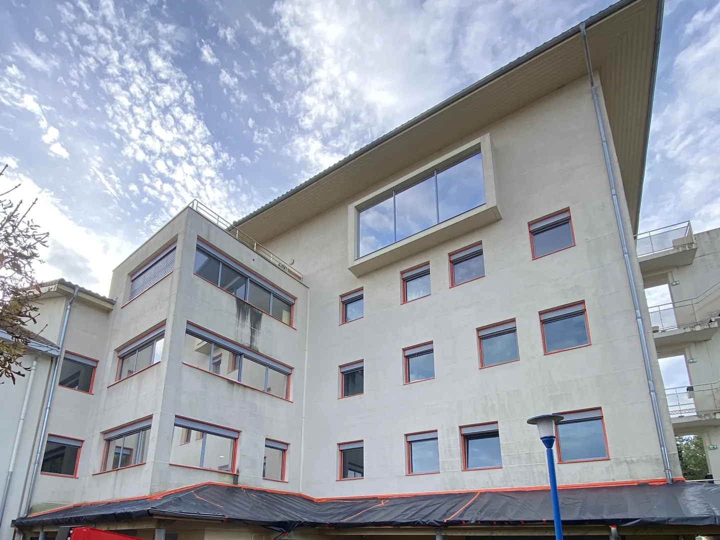 Avant : façade d'immeuble à Châtillon-sur-Chalaronne, enduit grisé et coulures sous les fenêtres, menuiseries protégées au ruban orange avant peinture