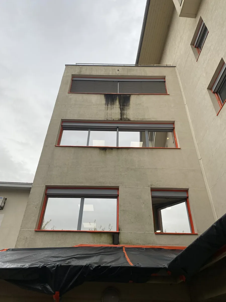 Façade d'immeuble à Châtillon-sur-Chalaronne, coulures noires d'humidité sous les fenêtres avant remise en peinture