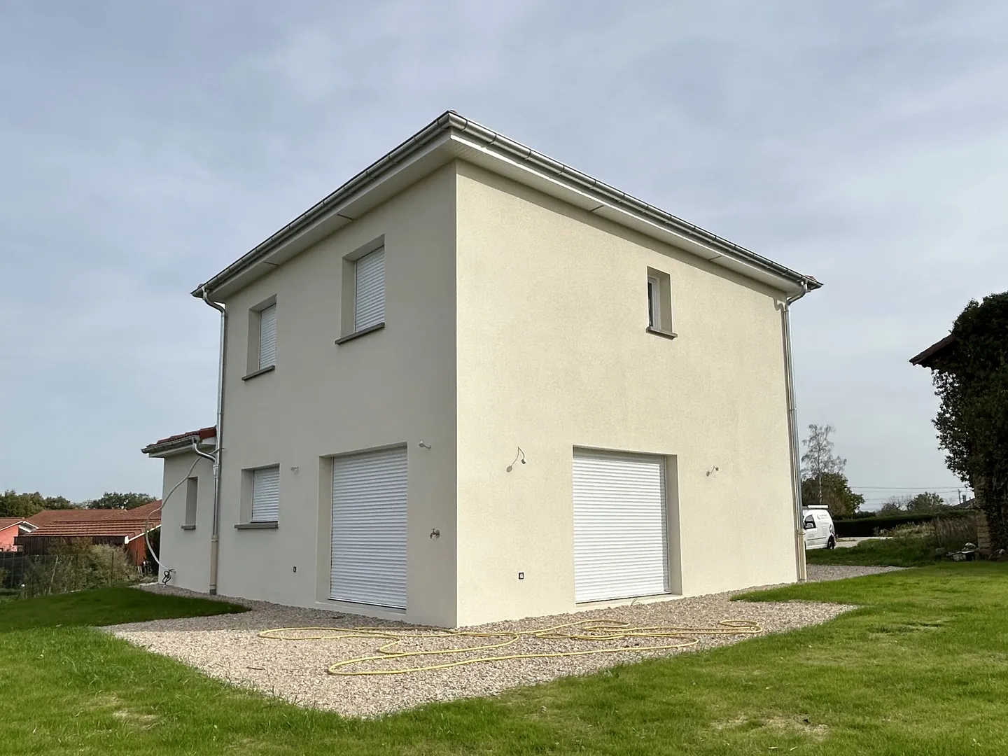 Maison neuve à Attignat, enduit de façade clair terminé, deux portes de garage