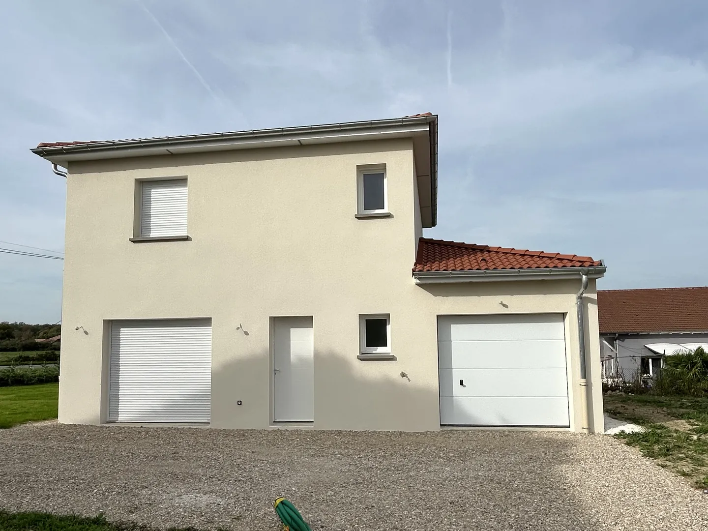La même maison neuve à Attignat vue de face, enduit clair, garage et allée gravillonnée