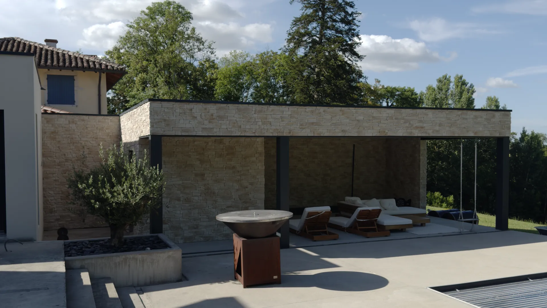 Villa à Buellas : pool-house habillé de parement de pierre claire, terrasse et piscine