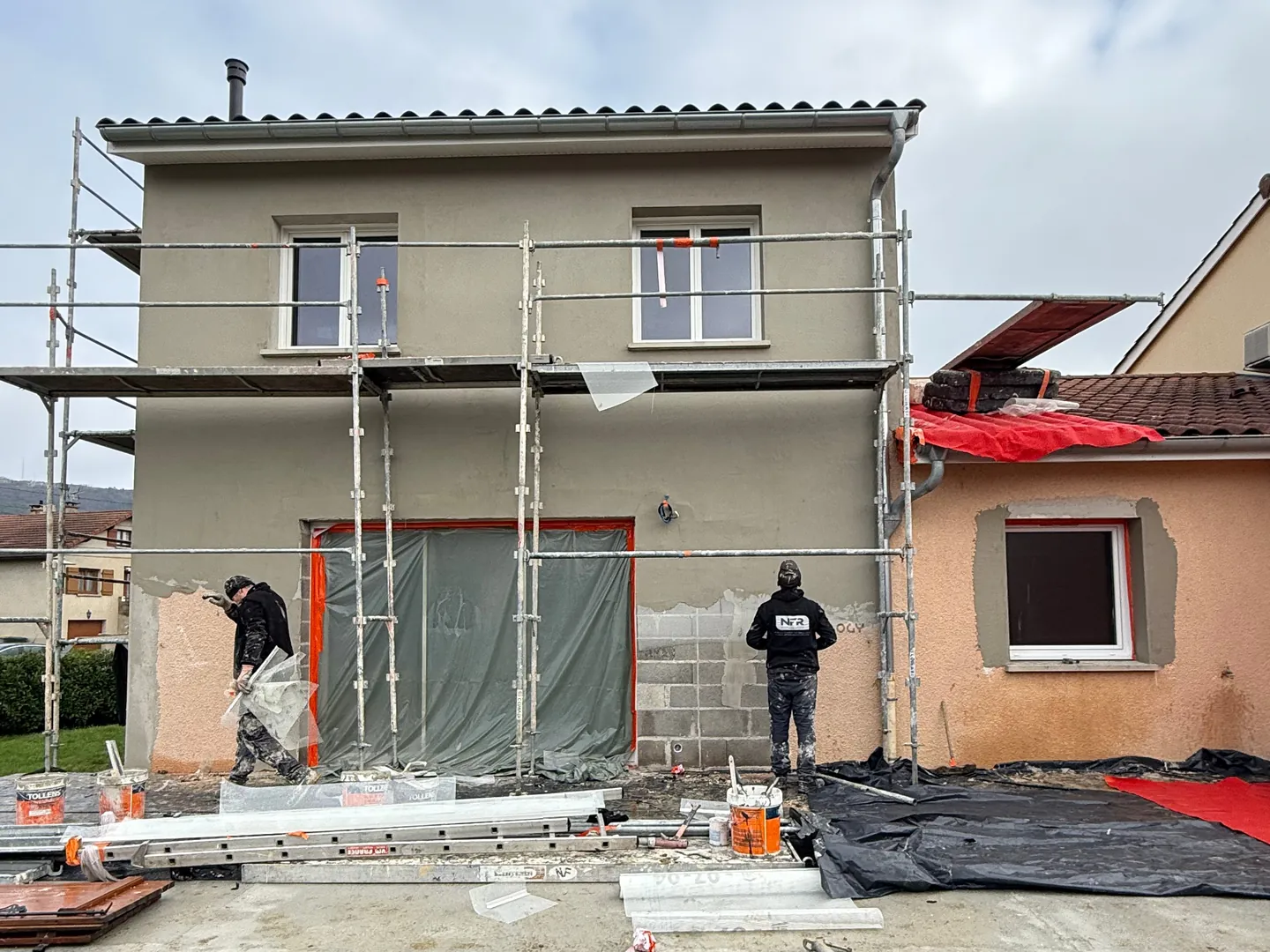 Artisans NFR au pied de la façade sous échafaudage à Ceyzériat, sous-enduit gris appliqué