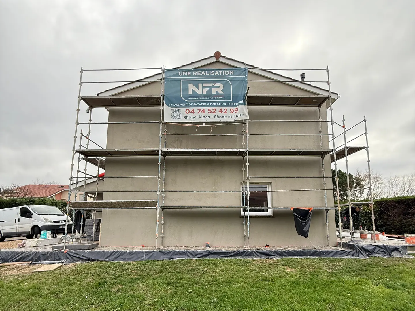 Pignon de la maison sous échafaudage avec la banderole NFR, à Ceyzériat