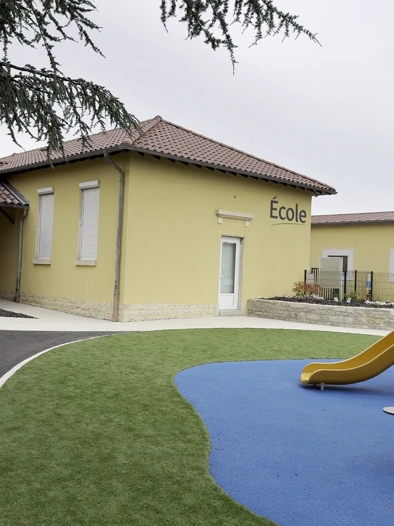 L'école de Confrançon après ravalement par NFR, façade jaune et soubassement en pierre, cour de récréation