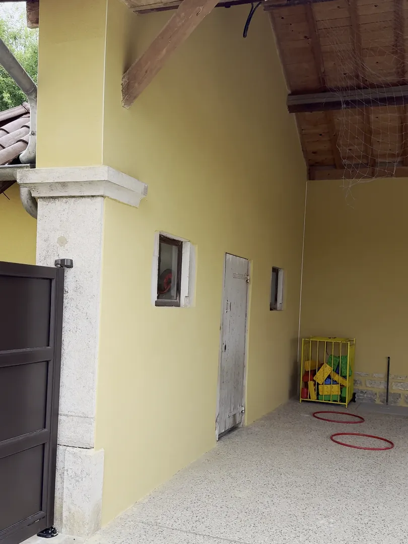 Préau de l'école de Confrançon, murs enduits en jaune, pilier en pierre et charpente bois