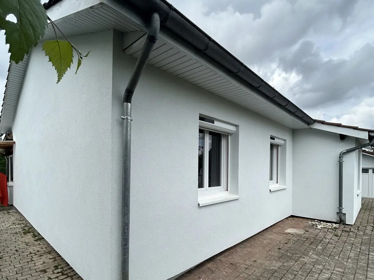 Angle d'une maison à Saint-André-de-Corcy, enduit de finition blanc, gouttière et descente neuves
