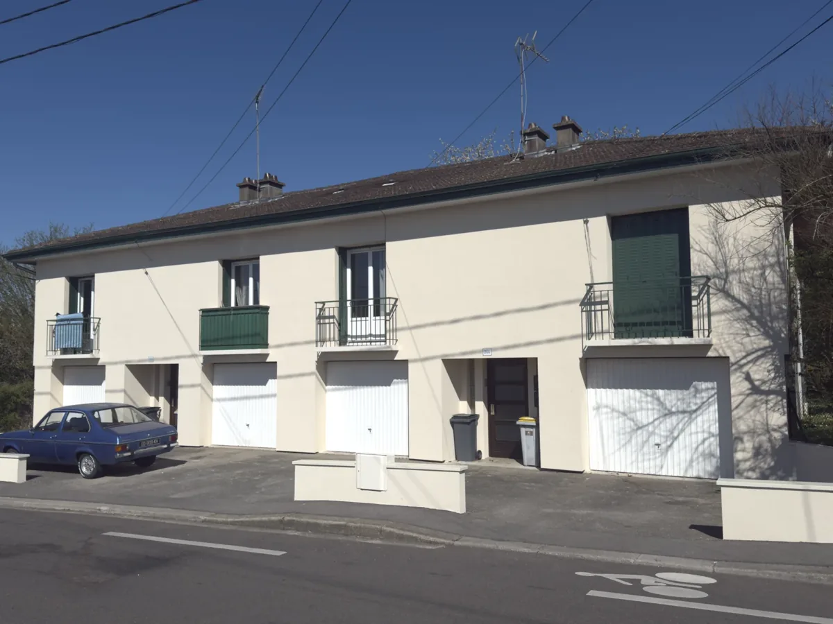 Rangée de maisons mitoyennes ravalée à l'enduit clair, balcons repris