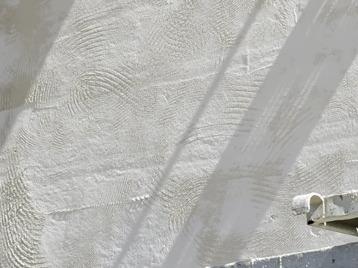 Gros plan d'un enduit à la chaux fraîchement taloché sur un mur en pisé, chantier NFR à Sandrans